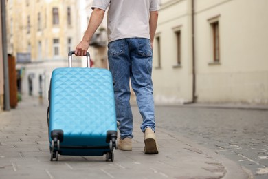 Photo of Goodbye. Man with luggage walking outdoors, closeup. Space for text