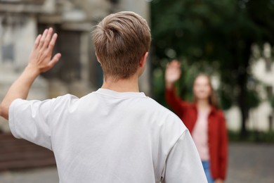 Photo of Goodbye. Man waving to his girlfriend outdoors, selective focus