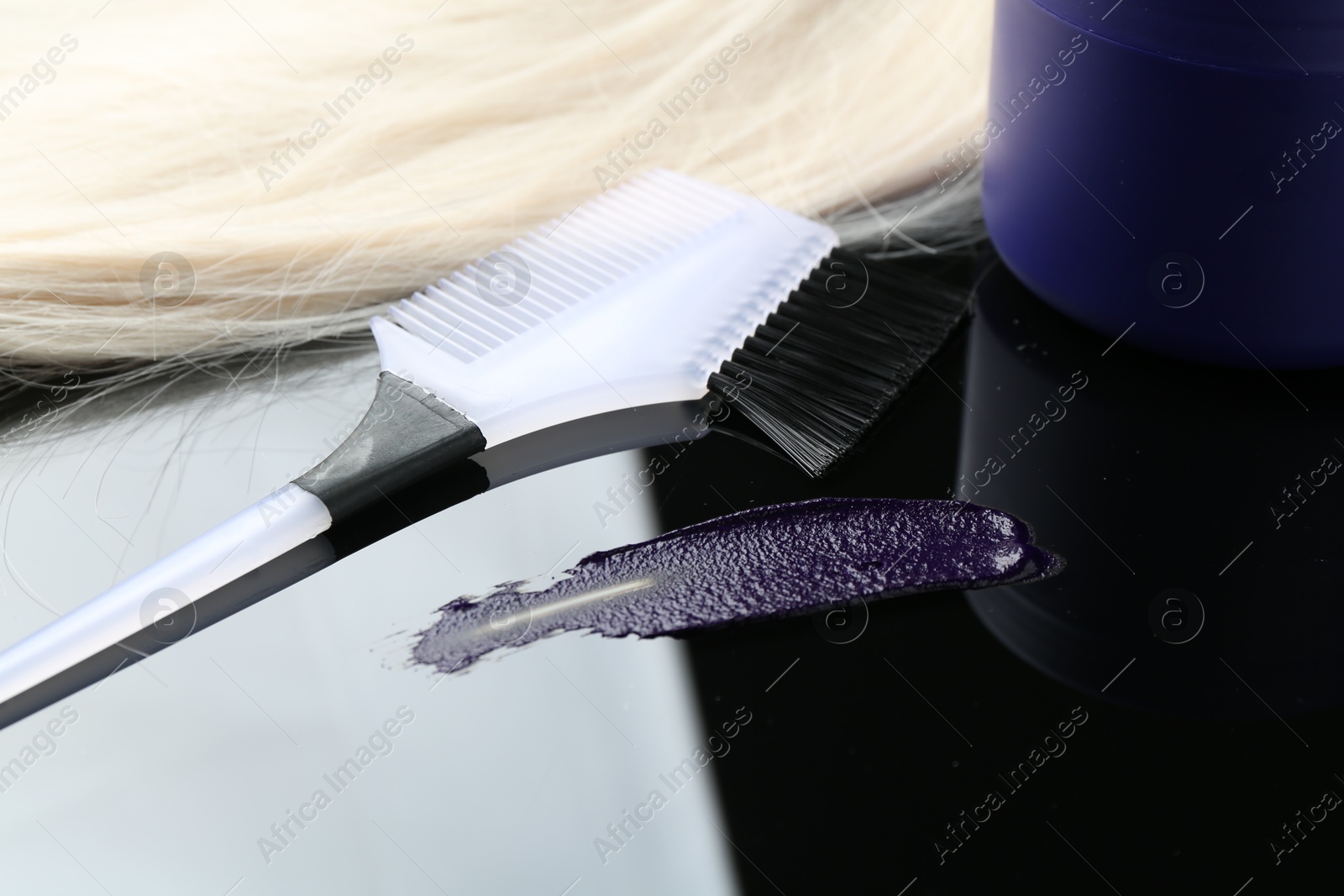 Hair care cosmetic product for blonde hair and brush on mirror surface, closeup Photo of Hair care cosmetic product for blonde hair and brush on mirror surface, closeup