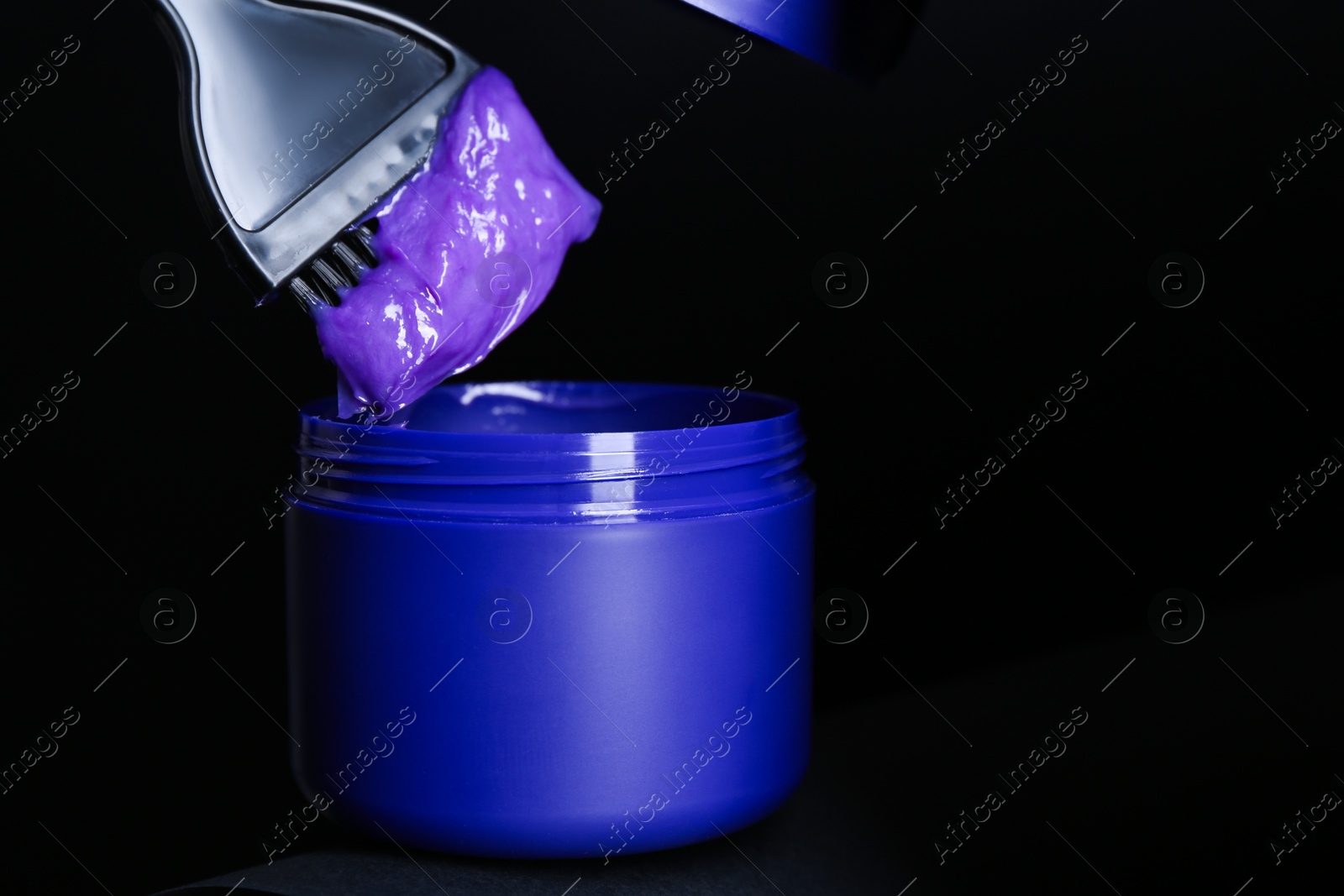 Brush with hair care cosmetic product for blonde hair over jar on black background, closeup. Space for text Photo of Brush with hair care cosmetic product for blonde hair over jar on black background, closeup. Space for text