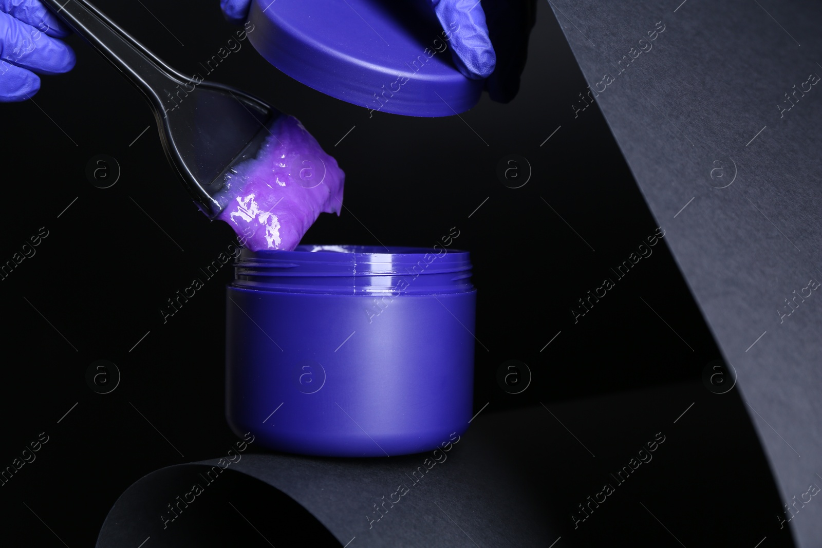 Woman taking hair care product for blonde hair with brush on black background, closeup Photo of Woman taking hair care product for blonde hair with brush on black background, closeup