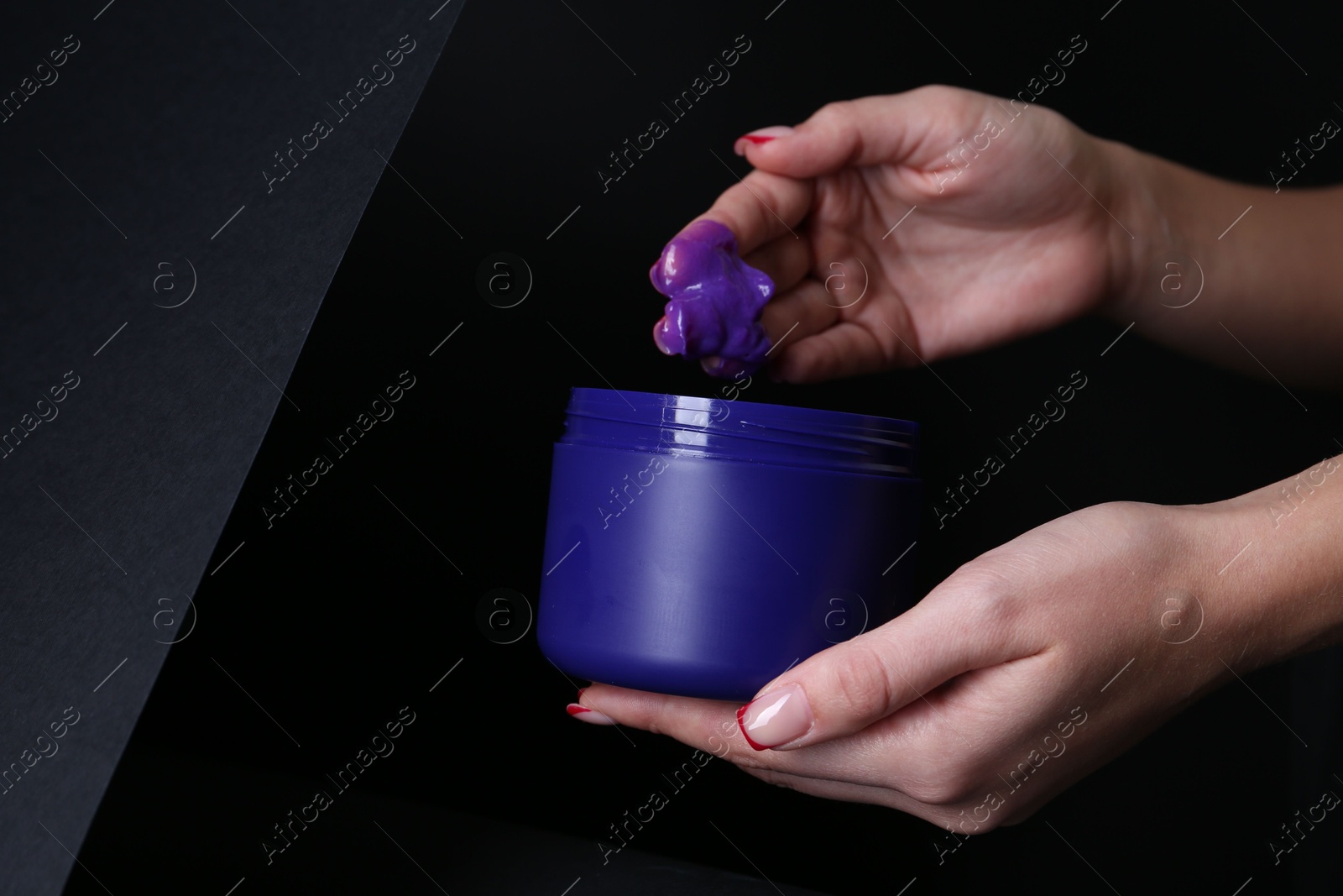 Woman taking hair care cosmetic product for blonde hair against black background, closeup. Space for text Photo of Woman taking hair care cosmetic product for blonde hair against black background, closeup. Space for text