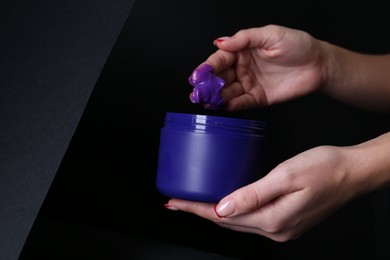Photo of Woman taking hair care cosmetic product for blonde hair against black background, closeup. Space for text
