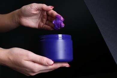 Photo of Woman taking hair care cosmetic product for blonde hair against black background, closeup. Space for text