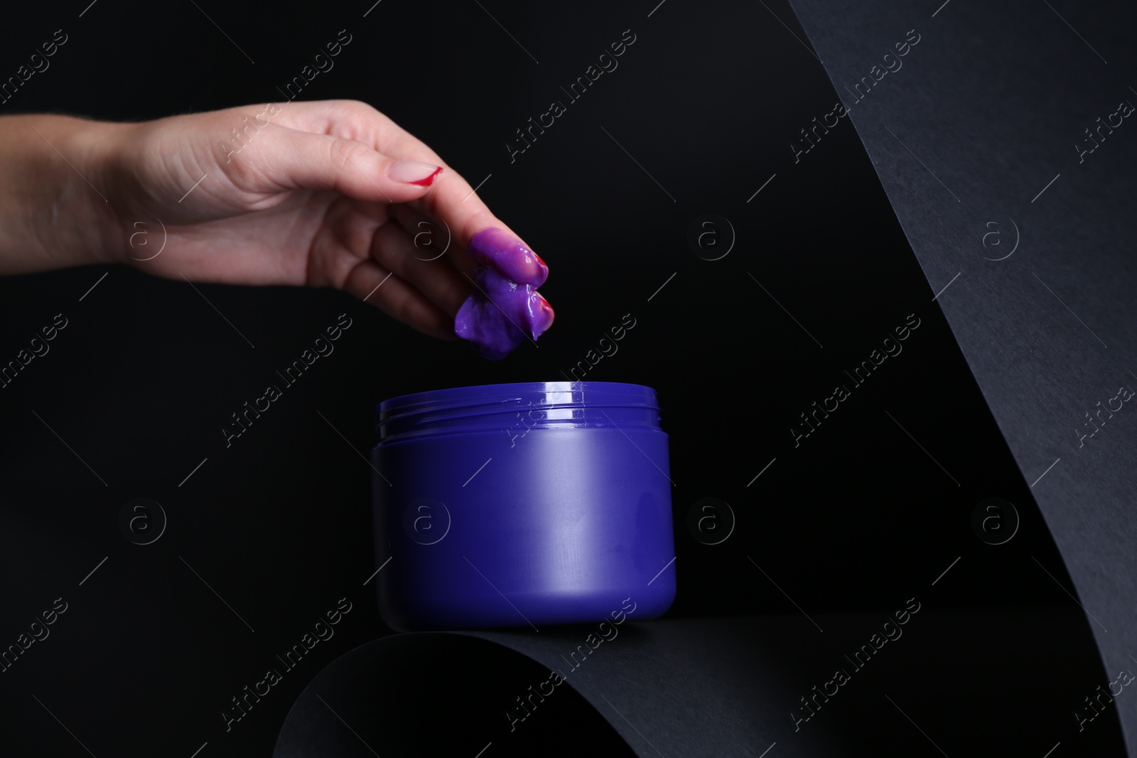 Woman taking hair care cosmetic product for blonde hair against black background, closeup. Space for text Photo of Woman taking hair care cosmetic product for blonde hair against black background, closeup. Space for text