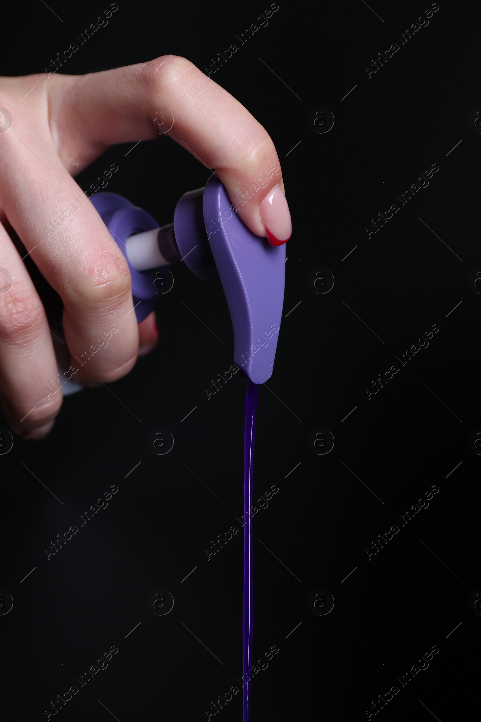 Woman using hair care cosmetic product for blonde hair on black background, closeup Photo of Woman using hair care cosmetic product for blonde hair on black background, closeup
