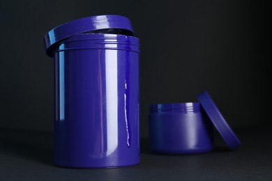 Photo of Jars of hair care cosmetic products for blonde hair on black background
