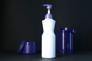 Photo of Different hair care cosmetic products for blonde hair on black background