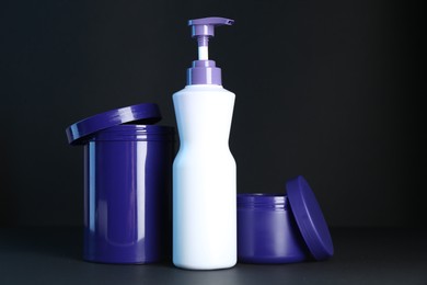 Photo of Different hair care cosmetic products for blonde hair on black background