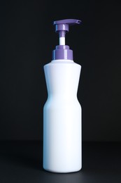 Photo of Bottle of hair care cosmetic products for blonde hair on black background