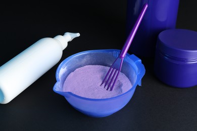 Photo of Hair care cosmetic products for blonde hair, powder and spatula on black background, closeup
