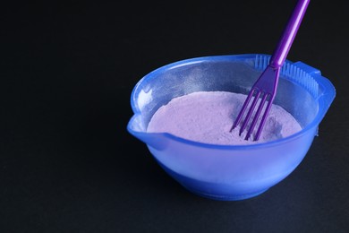 Photo of Blonde hair care cosmetic product. Powder in bowl and spatula on black background, closeup. Space for text