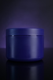 Photo of Jar of hair care cosmetic product for blonde hair on dark purple background