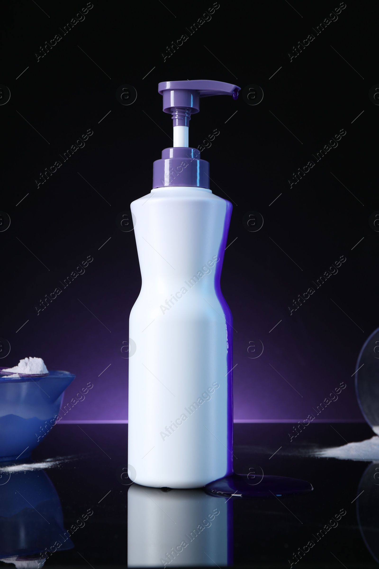 Hair care cosmetic product for blonde hair and powder on black mirror surface against dark purple background Photo of Hair care cosmetic product for blonde hair and powder on black mirror surface against dark purple background