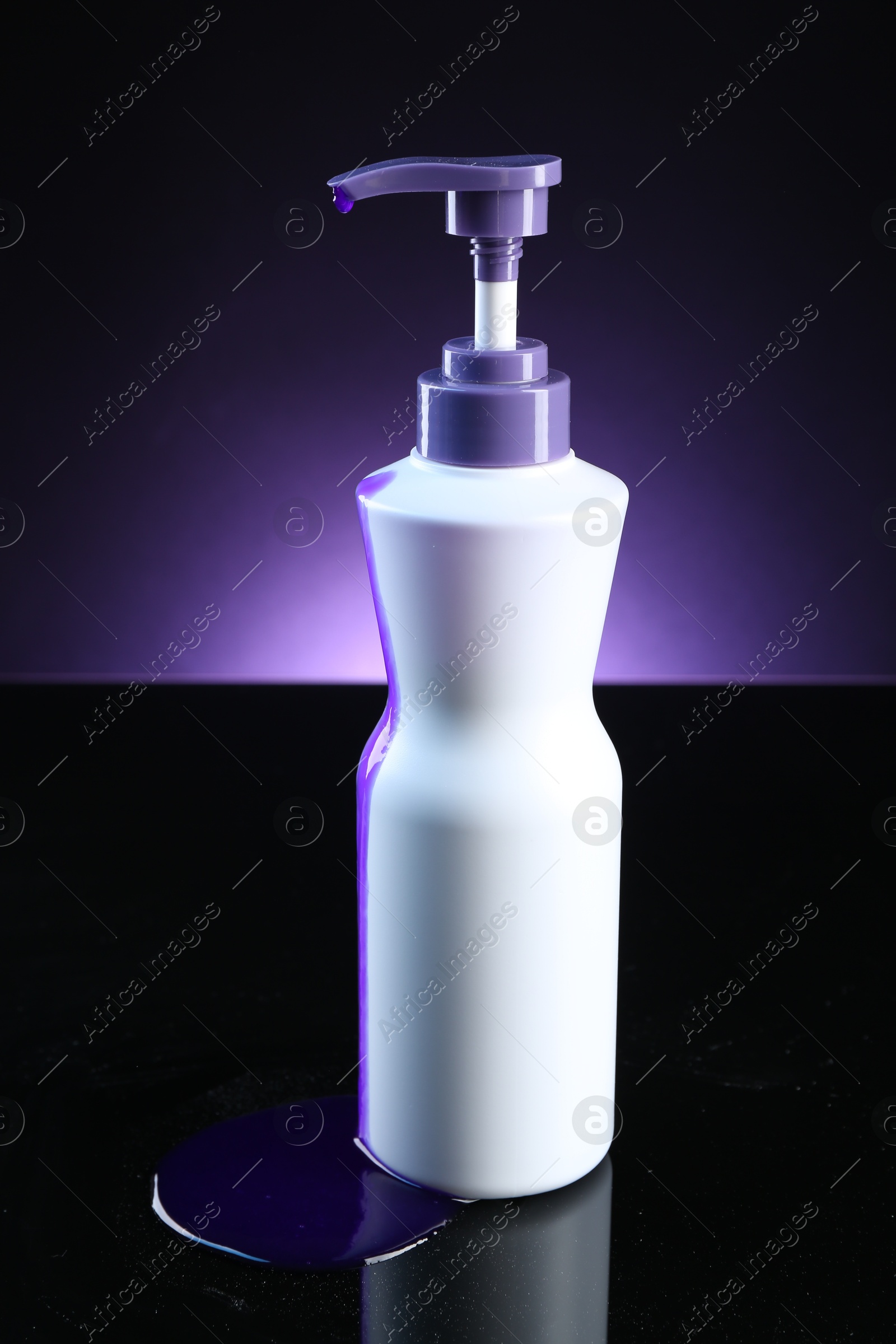 Bottle of hair care cosmetic products for blonde hair on black mirror surface against dark purple background Photo of Bottle of hair care cosmetic products for blonde hair on black mirror surface against dark purple background