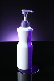 Photo of Bottle of hair care cosmetic products for blonde hair on black mirror surface against dark purple background