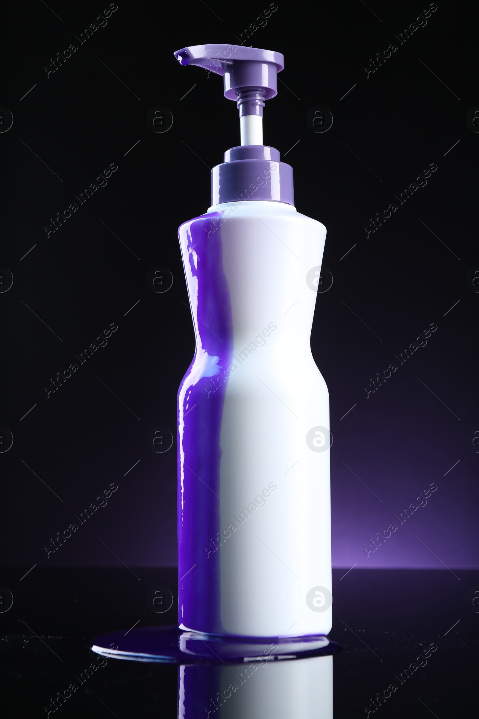 Bottle of hair care cosmetic products for blonde hair on black mirror surface against dark purple background Photo of Bottle of hair care cosmetic products for blonde hair on black mirror surface against dark purple background