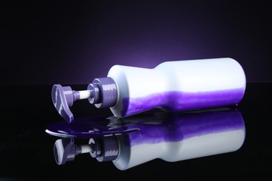 Photo of Bottle of hair care cosmetic products for blonde hair on black mirror surface against dark purple background