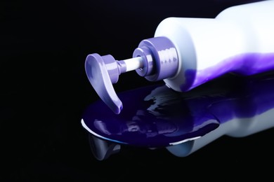 Photo of Bottle of hair care cosmetic products for blonde hair on black mirror surface, closeup. Space for text