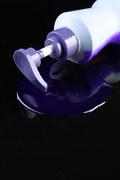 Photo of Bottle of hair care cosmetic products for blonde hair on black mirror surface, closeup