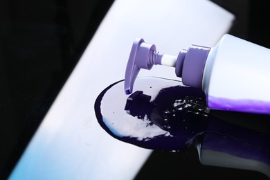 Photo of Bottle of hair care cosmetic products for blonde hair on black mirror surface, closeup. Space for text