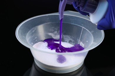 Photo of Woman making hair care product for blonde hair at black mirror table, closeup