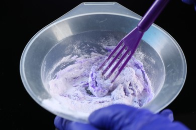 Photo of Woman making hair care cosmetic product for blonde hair on black background, closeup