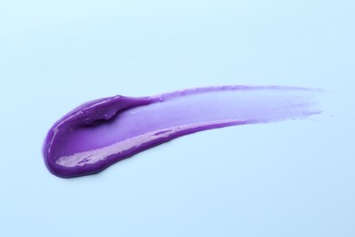Photo of Sample of blonde hair care cosmetic product on light blue background, top view