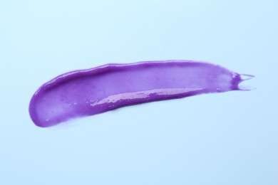 Photo of Sample of blonde hair care cosmetic product on light blue background, top view