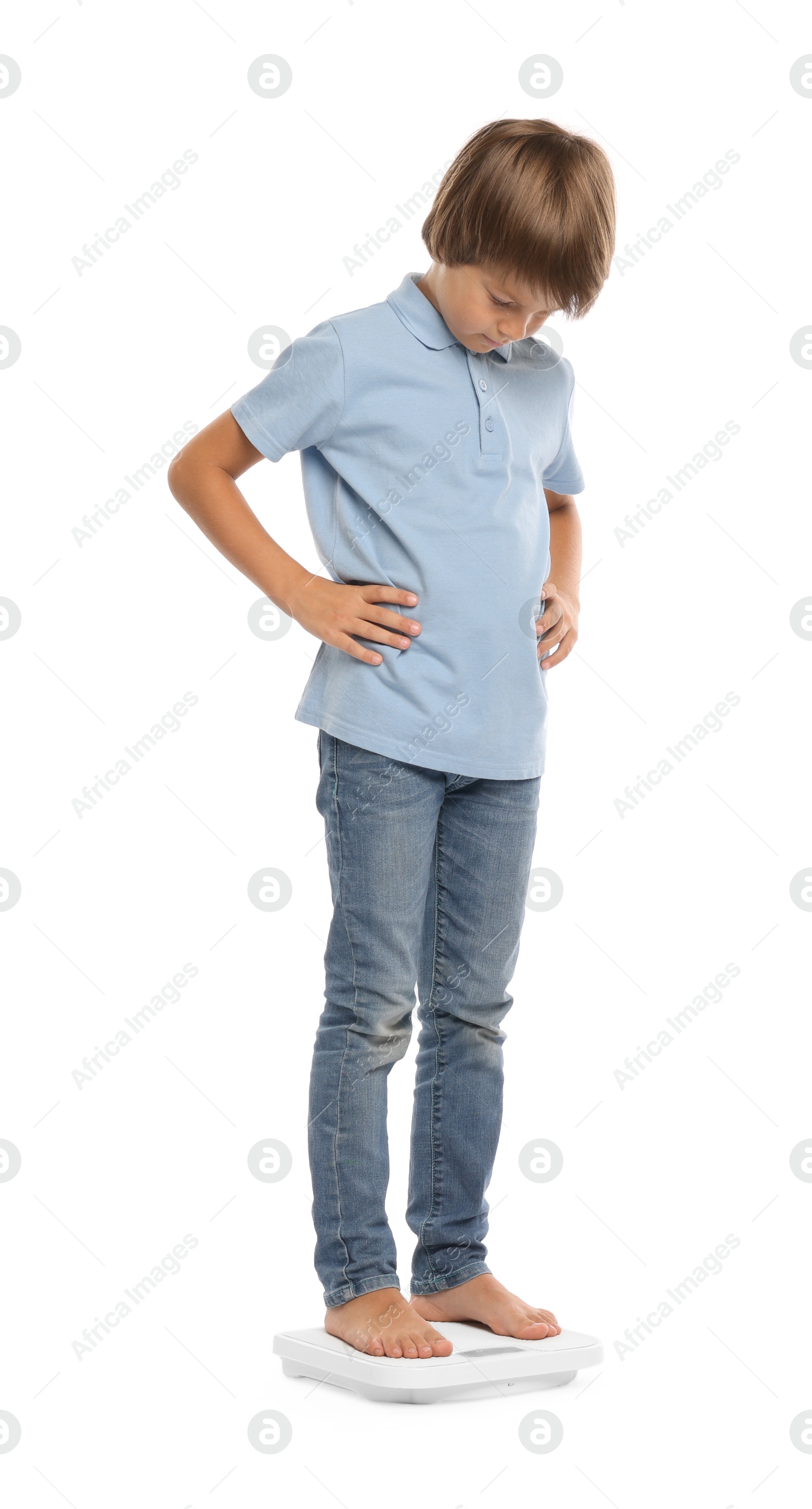 Little boy standing on scales against white background Photo of Little boy standing on scales against white background