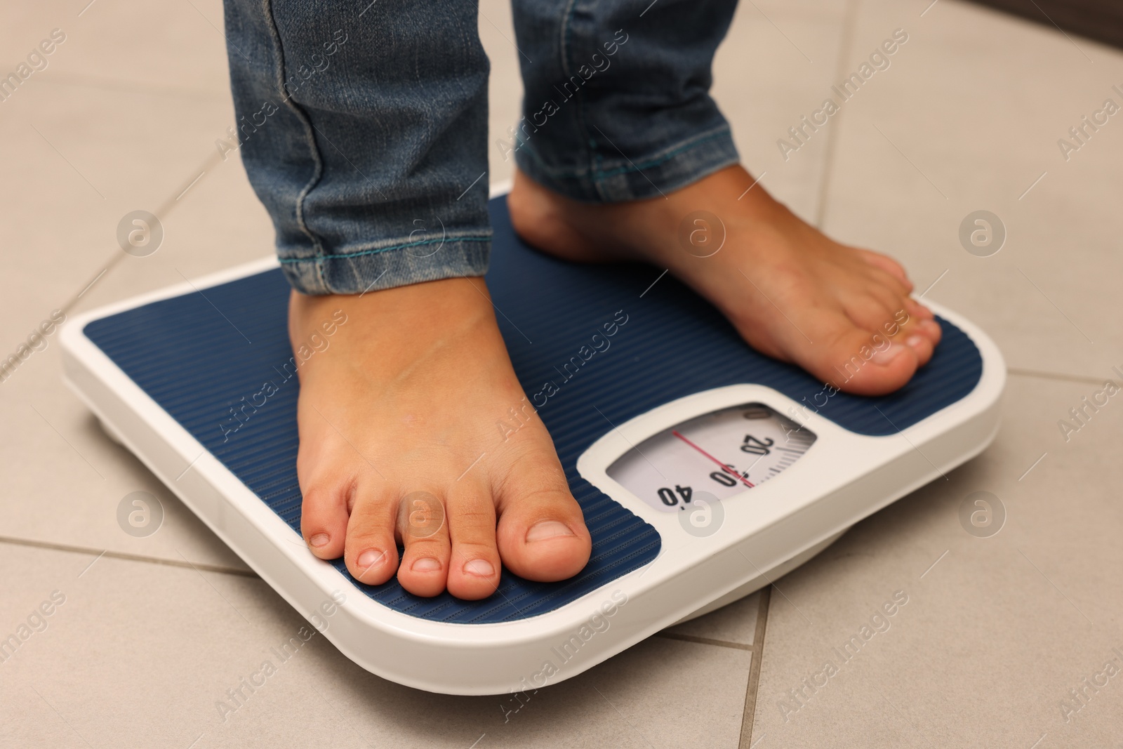 Photo of Little boy standing on scales indoors, closeup