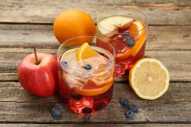 Photo of Tasty punch in glasses and fresh fruits on wooden table, closeup. Refreshing drink