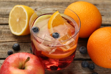 Photo of Tasty punch in glass and fresh fruits on wooden table, closeup. Refreshing drink