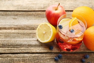 Photo of Tasty punch in glass and fresh fruits on wooden table, closeup. Refreshing drink