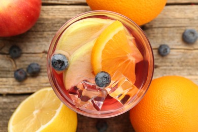 Photo of Tasty punch in glass and fresh fruits on wooden table, flat lay. Refreshing drink