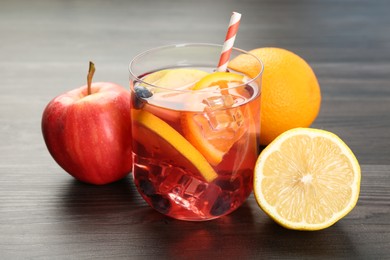 Photo of Tasty punch in glass and fresh fruits on wooden table, closeup. Refreshing drink