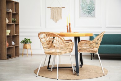 Photo of Wooden table with candles and stylish chairs in dining room