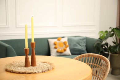 Photo of Wooden table with candles and stylish chair in dining room, closeup