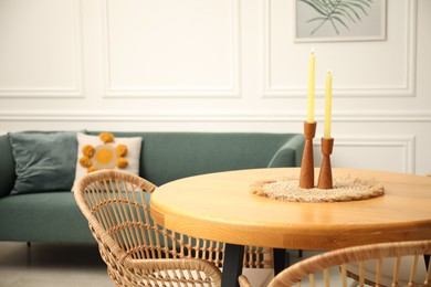 Photo of Wooden table with candles and stylish chairs in dining room, closeup