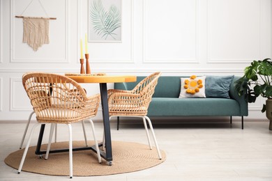 Photo of Wooden table with candles and stylish chairs in dining room