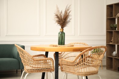 Photo of Wooden table with decor and stylish chairs in dining room