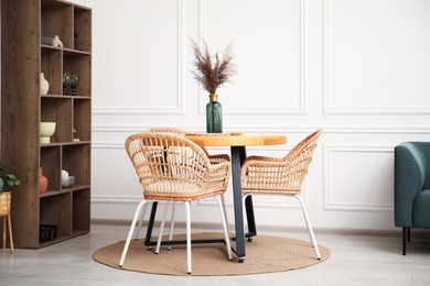 Photo of Wooden table with decor and stylish chairs in dining room