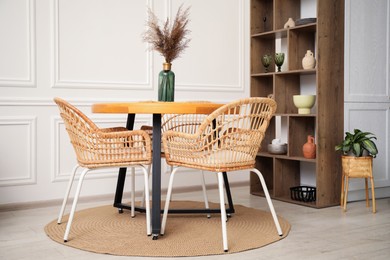 Photo of Wooden table with decor and stylish chairs in dining room