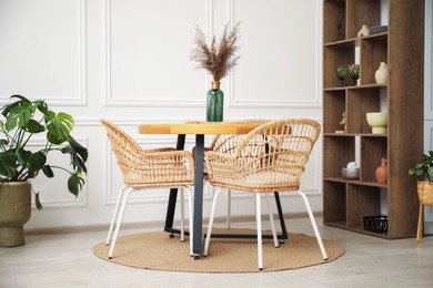 Photo of Wooden table with decor and stylish chairs in dining room