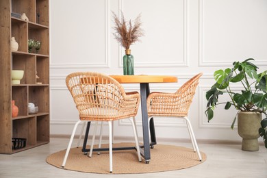 Photo of Wooden table with decor and stylish chairs in dining room