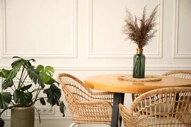Photo of Wooden table with decor and stylish chairs in dining room