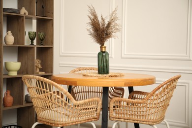 Photo of Wooden table with decor and stylish chairs in dining room