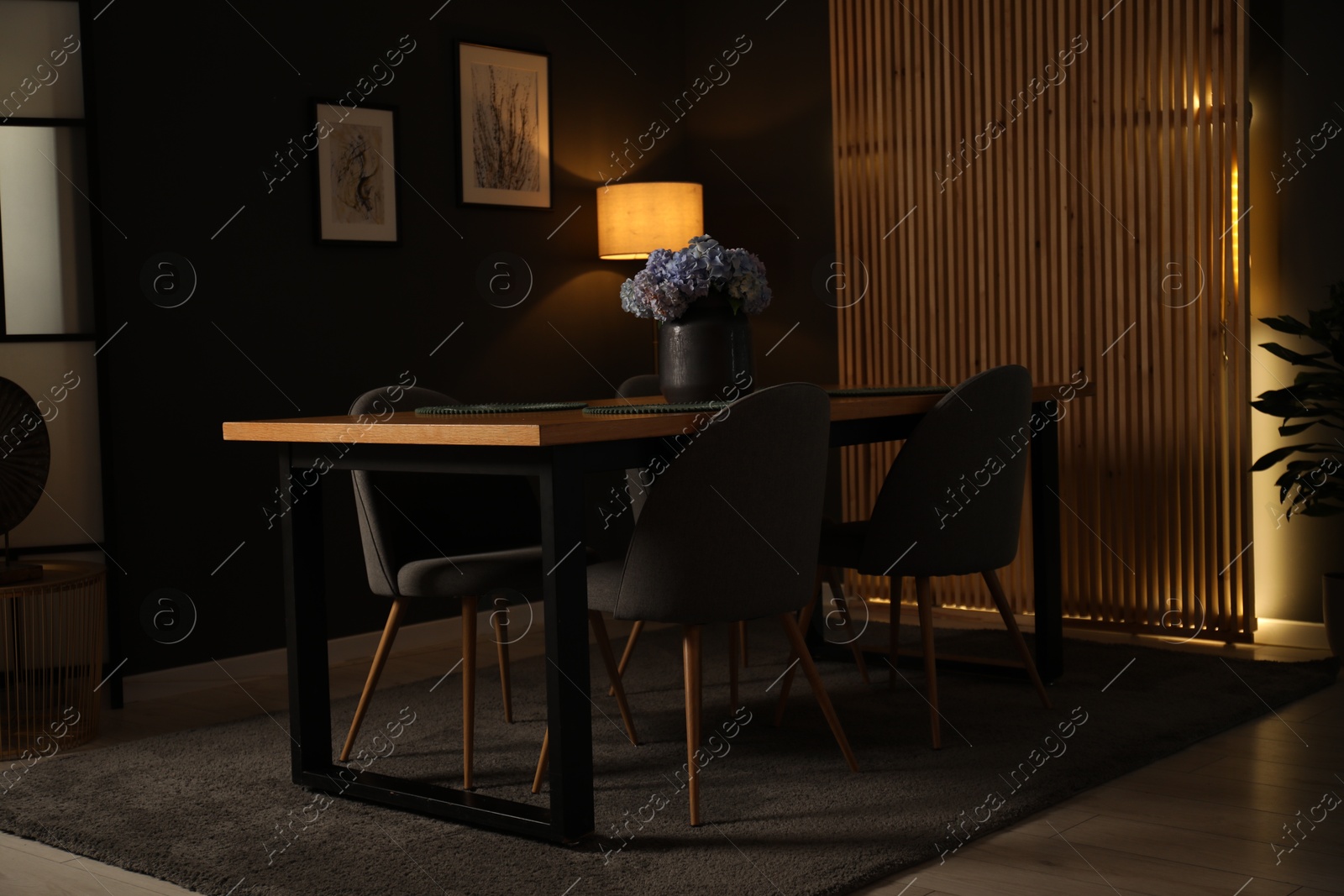 Photo of Wooden table with beautiful flowers and chairs in dining room at night