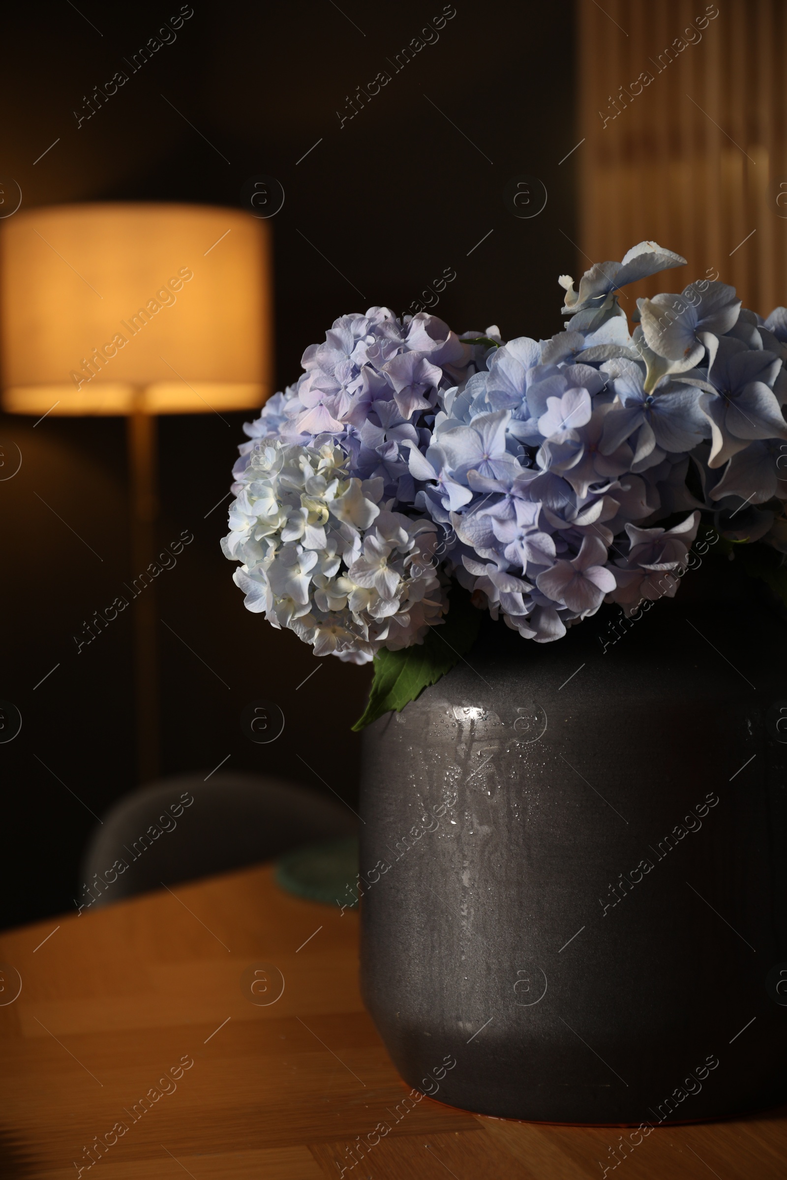 Beautiful flowers on wooden table in dining at night, closeup Photo of Beautiful flowers on wooden table in dining at night, closeup