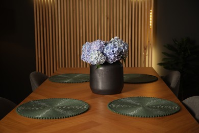 Photo of Wooden table with beautiful flowers and chairs in dining room at night
